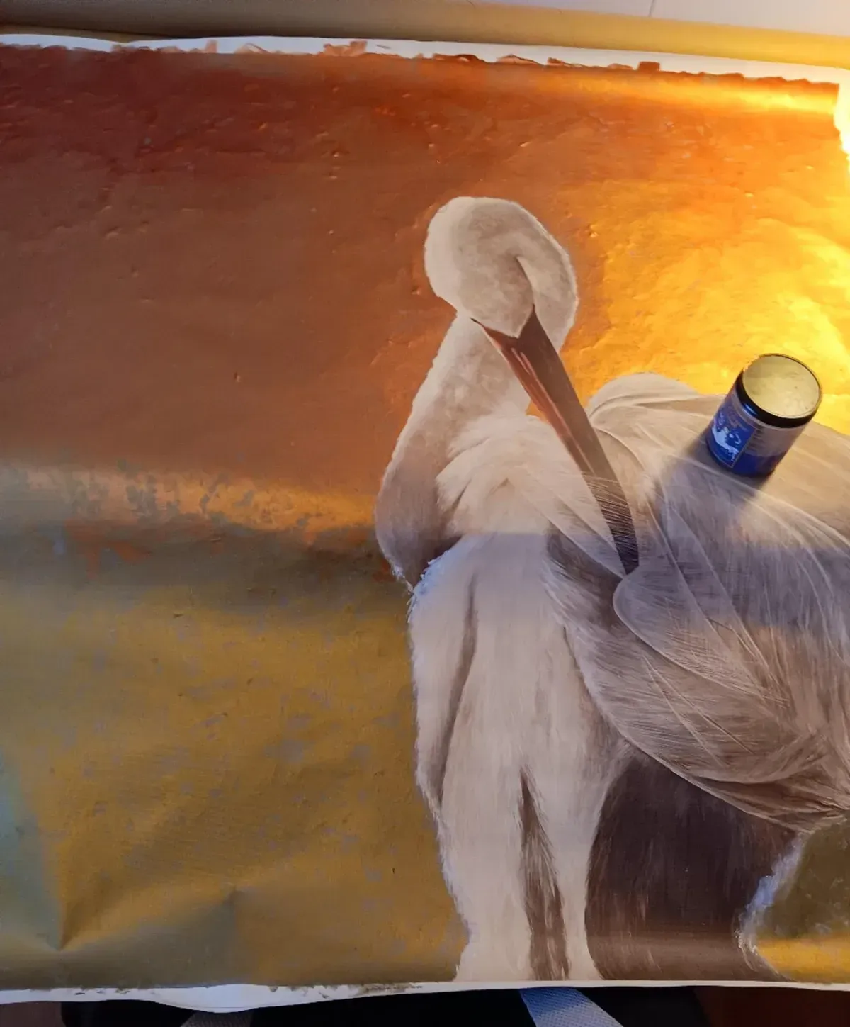 Pelican preening against a golden background. Bird is white with a brown beak.
