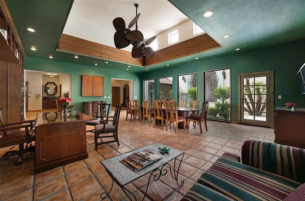 Spacious room with green walls, brick floor, skylight, dining area, and seating.