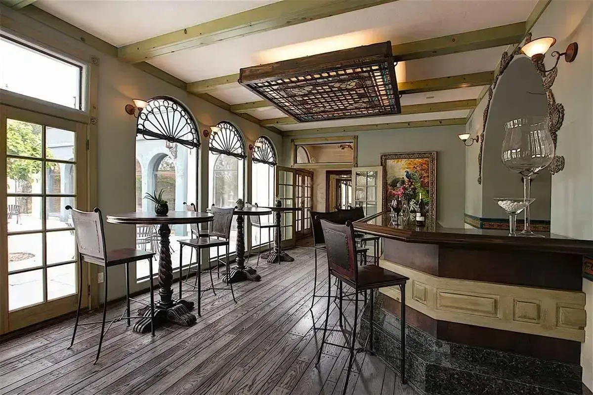 Interior bar with high tables, arched windows, and a decorative ceiling panel.