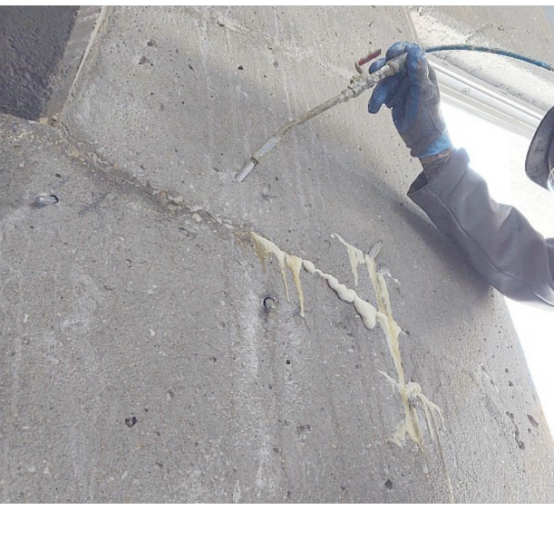A person is spraying foam on a concrete wall