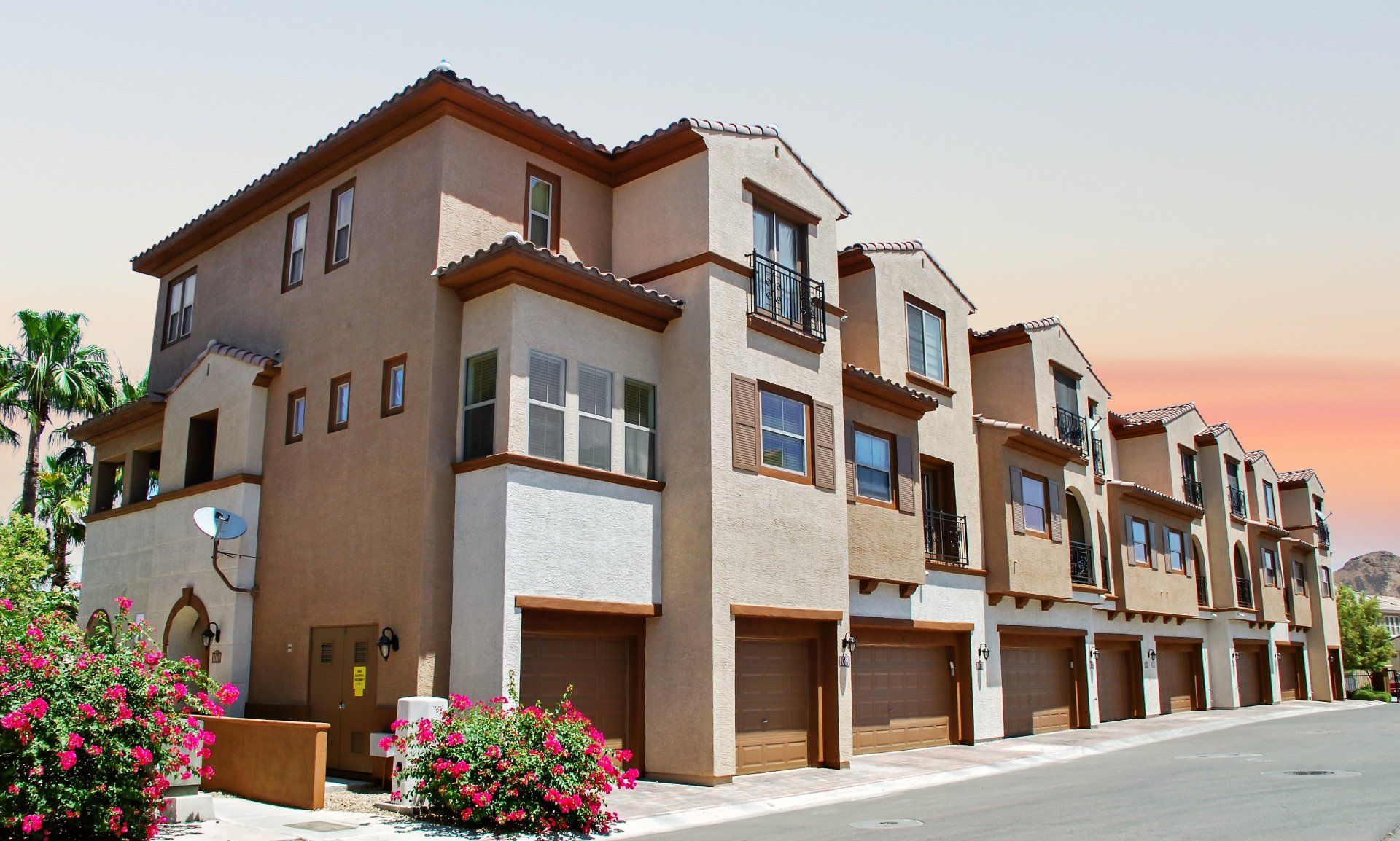 A row of apartment buildings with a sunset in the background