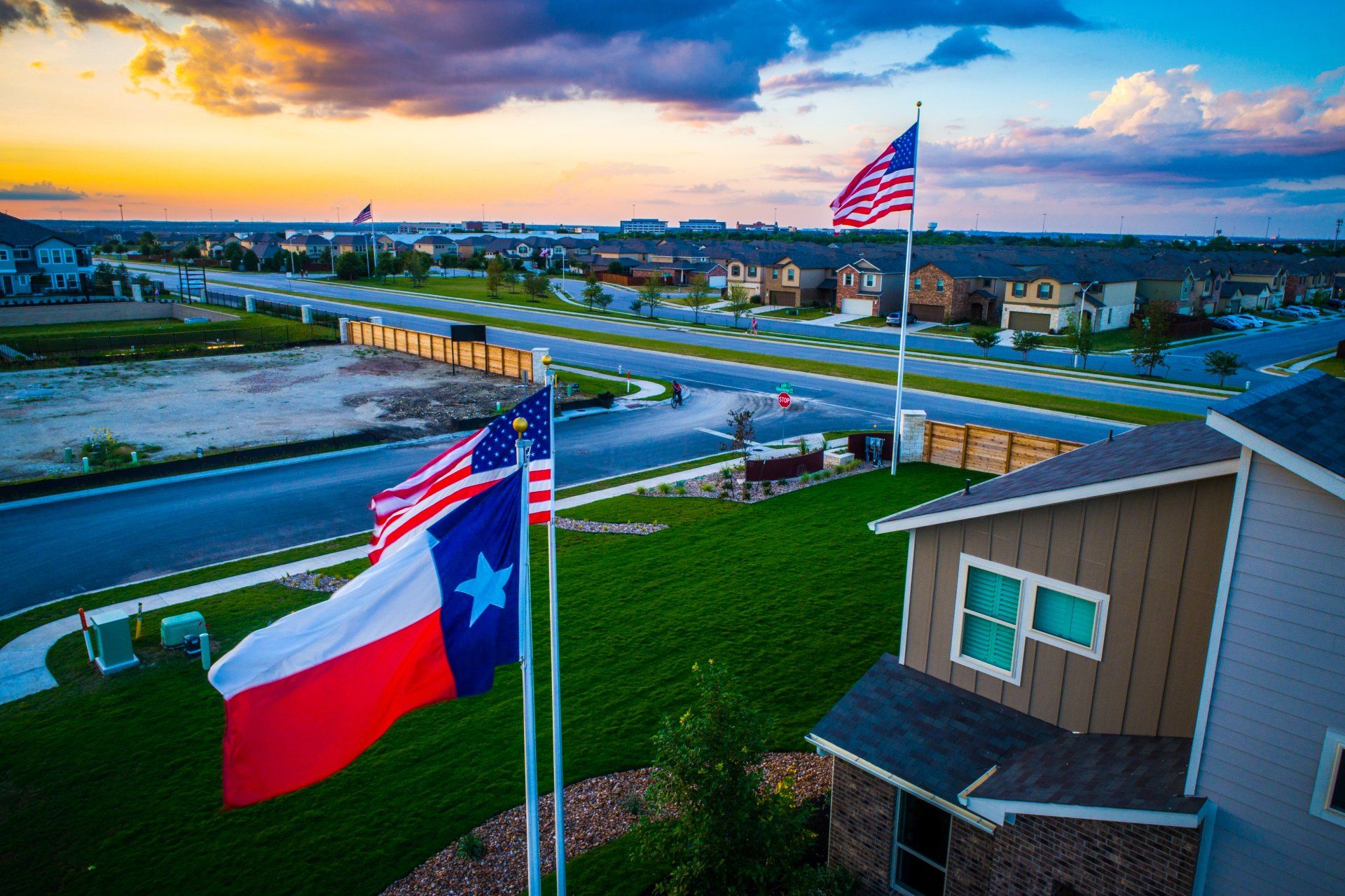 An aerial view of a texas flag and an american flag flying in front of a house.