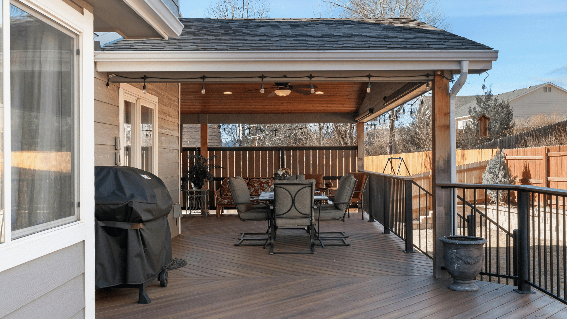 A large deck with a table and chairs and a grill.
