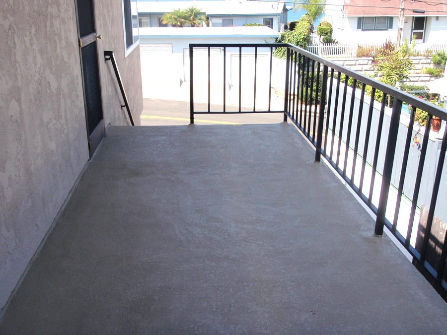 A balcony with a metal railing and a concrete floor.