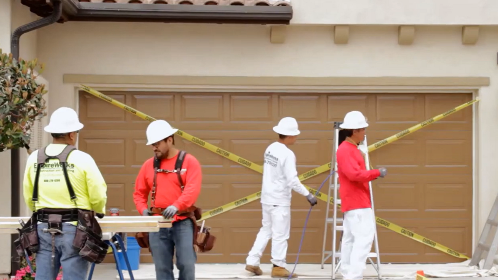 A group of construction workers are working on a garage door.