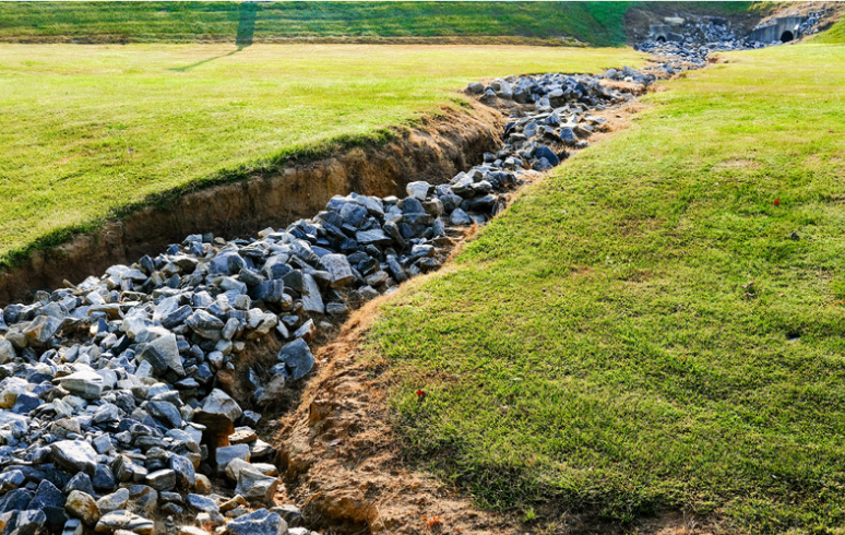 A stream of rocks is running through a grassy field.