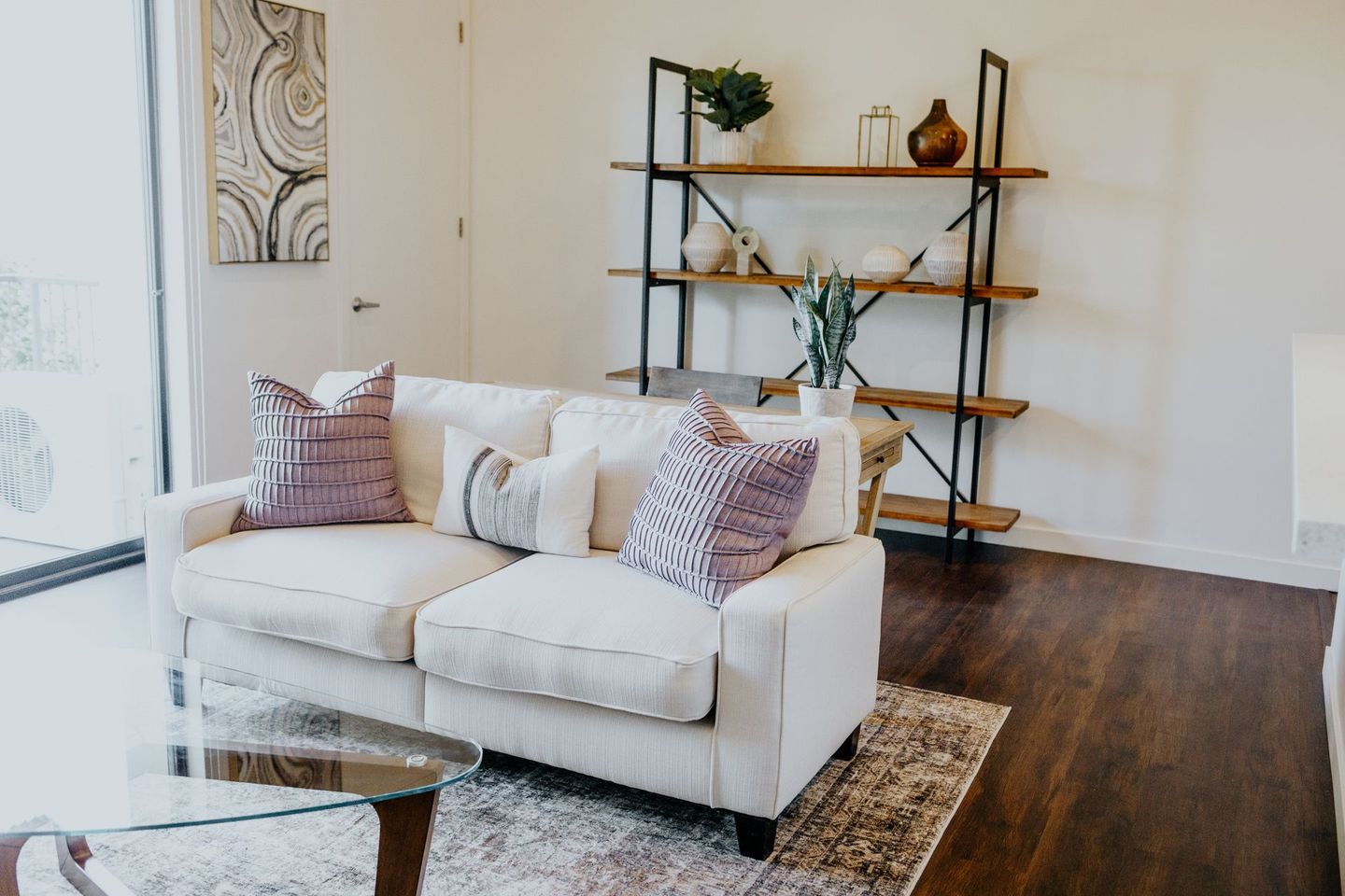 A bedroom with a bed , dresser , nightstand , mirror and shelves.