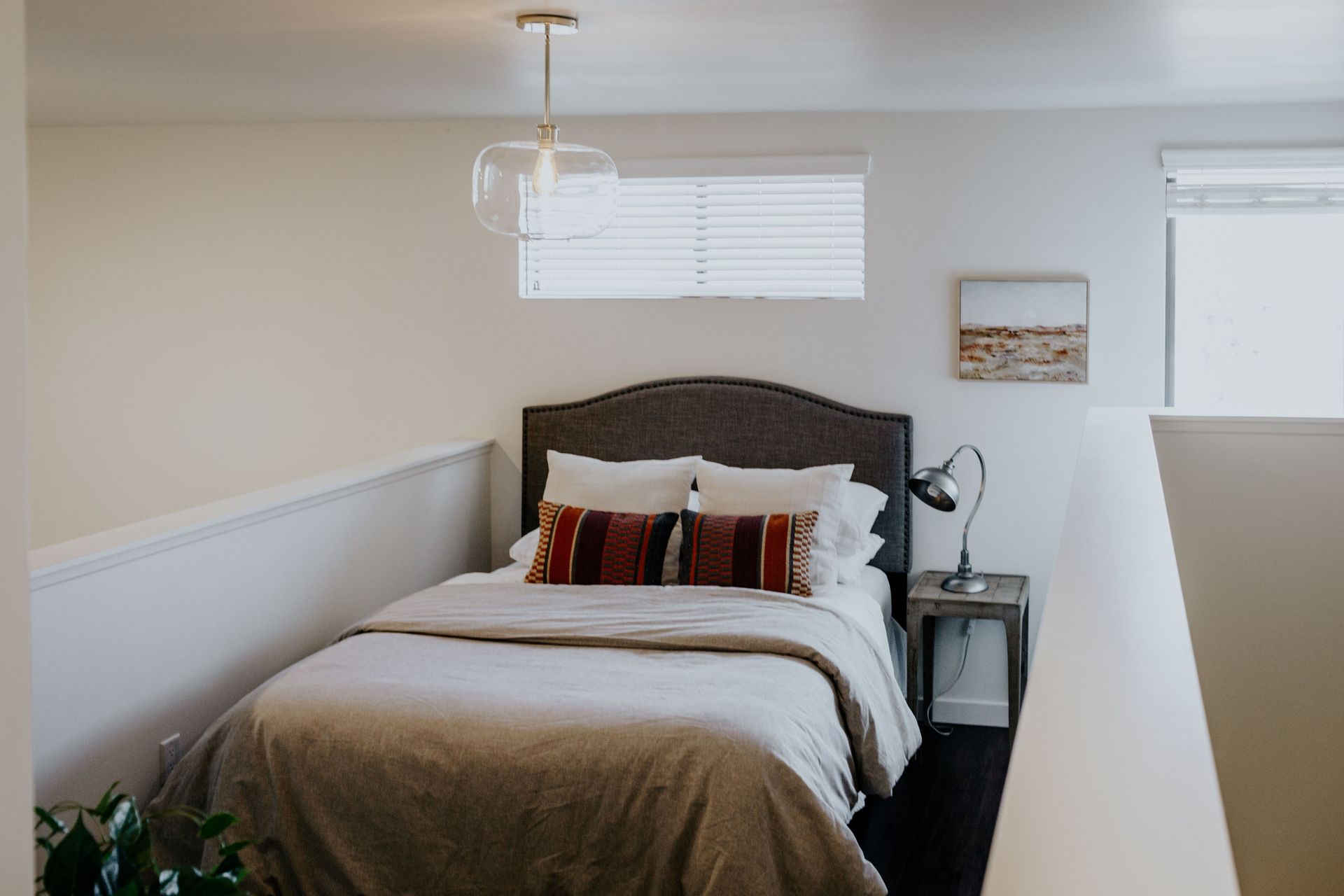 Loft bedroom with a queen-sized bed, nightstand, small desk, and dresser.