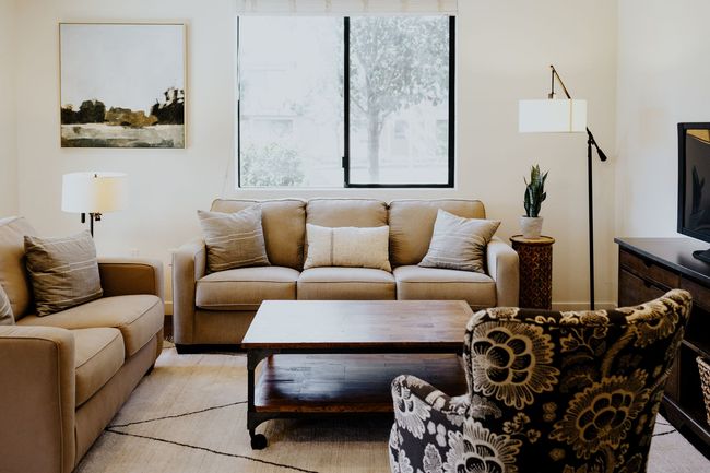 A living room with a couch , chair , coffee table and television.