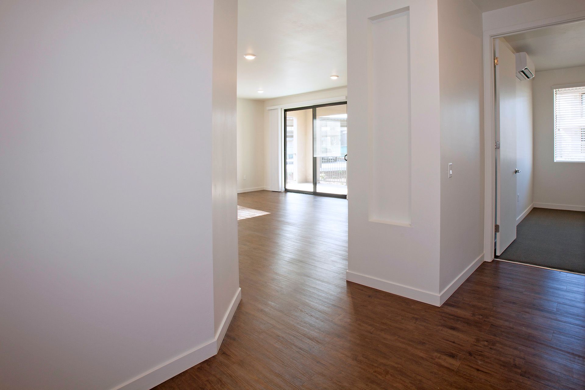 An empty apartment with hardwood floors and white walls.
