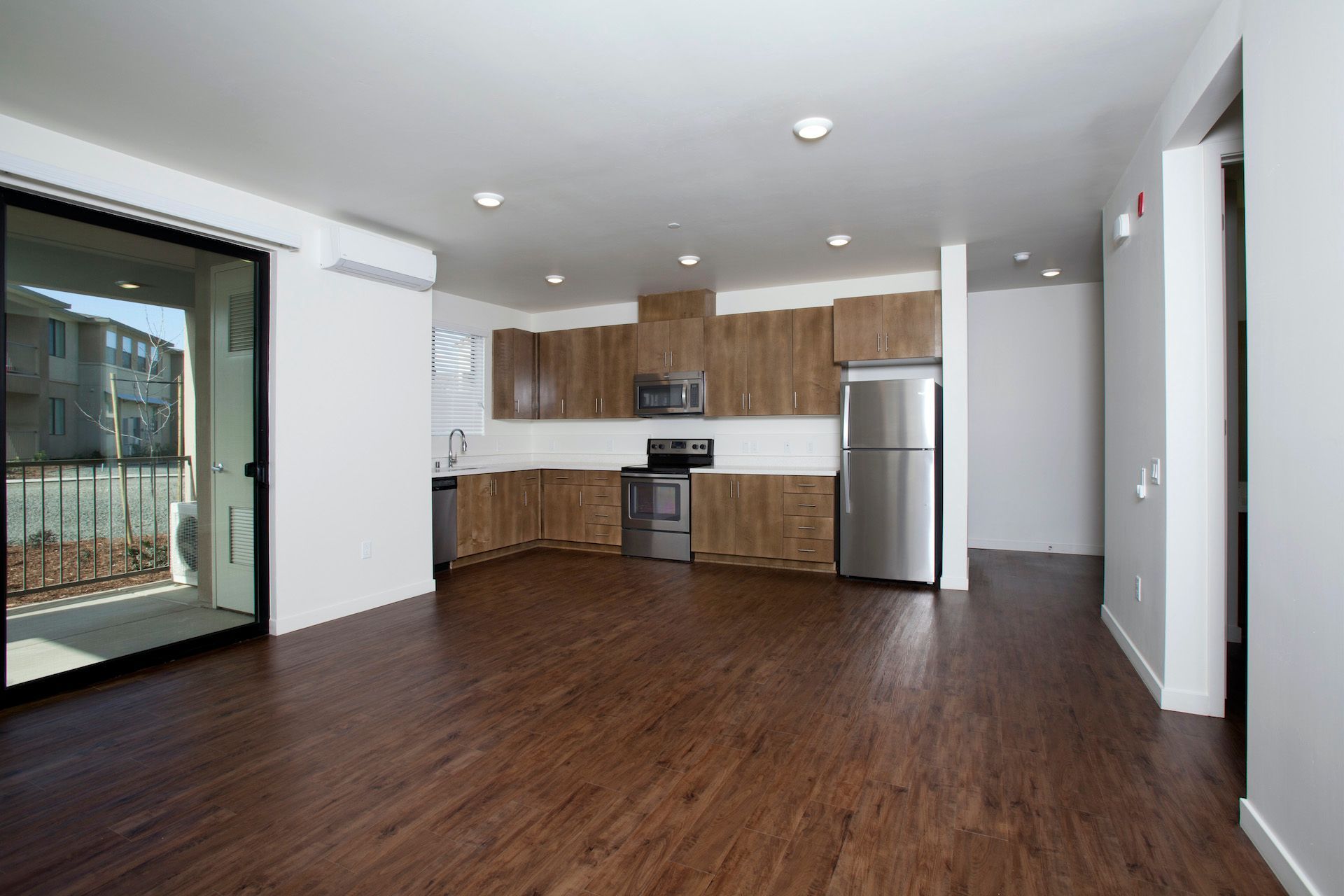An empty kitchen with stainless steel appliances and wooden cabinets