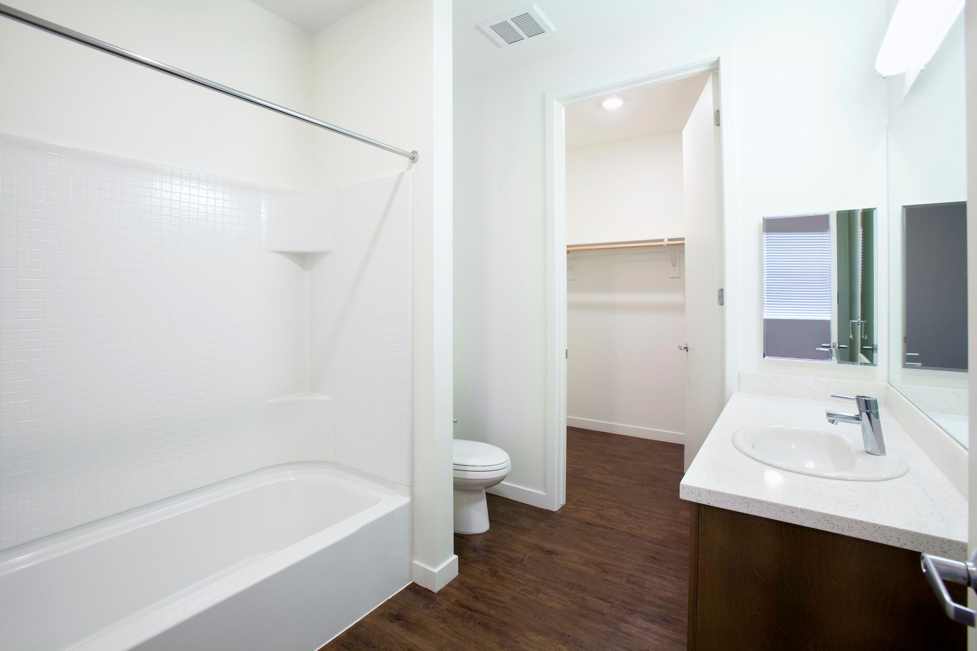 A bathroom with a tub , toilet , sink and mirror.