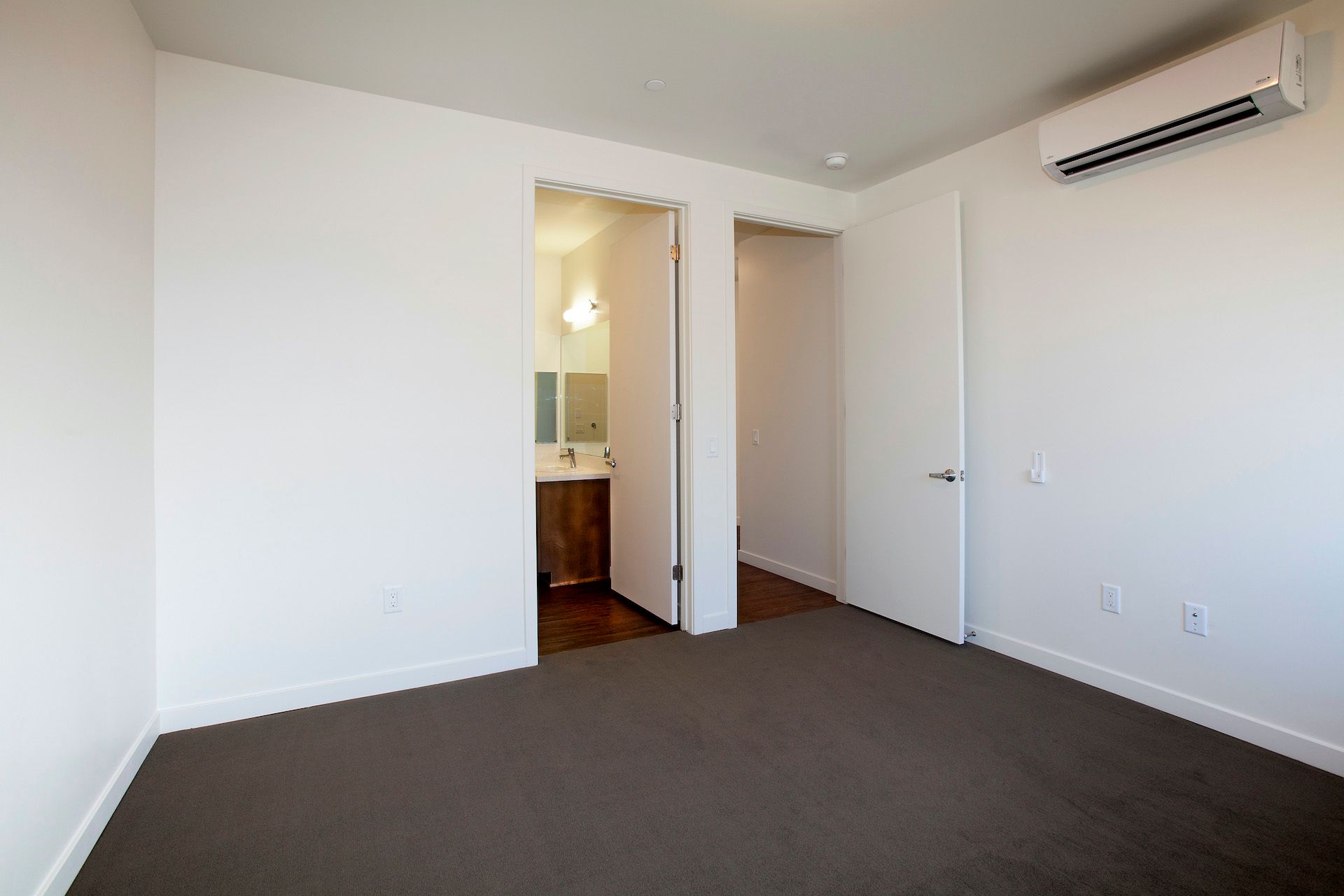 An empty bedroom with a carpeted floor and white walls.