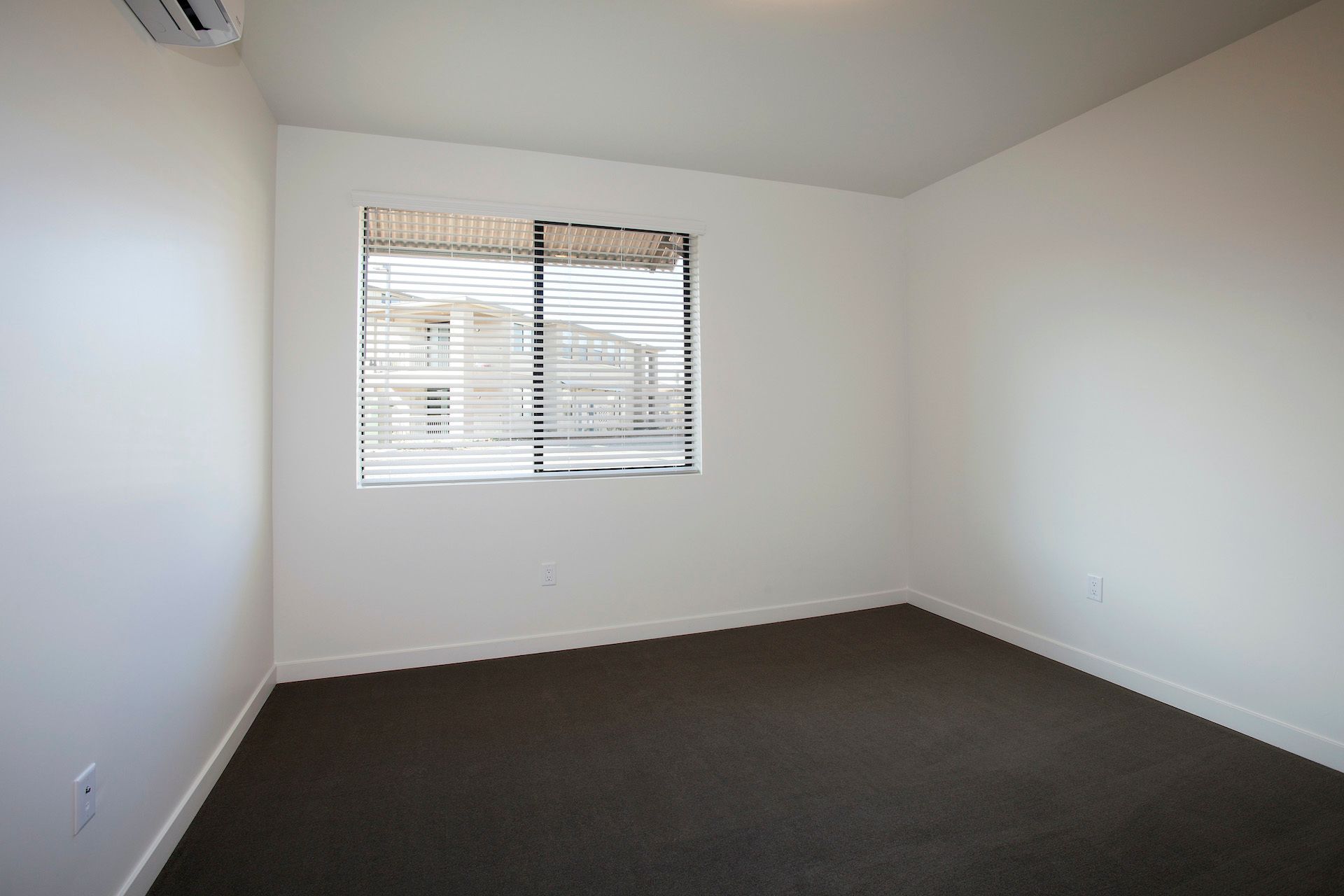 An empty bedroom with a window and blinds