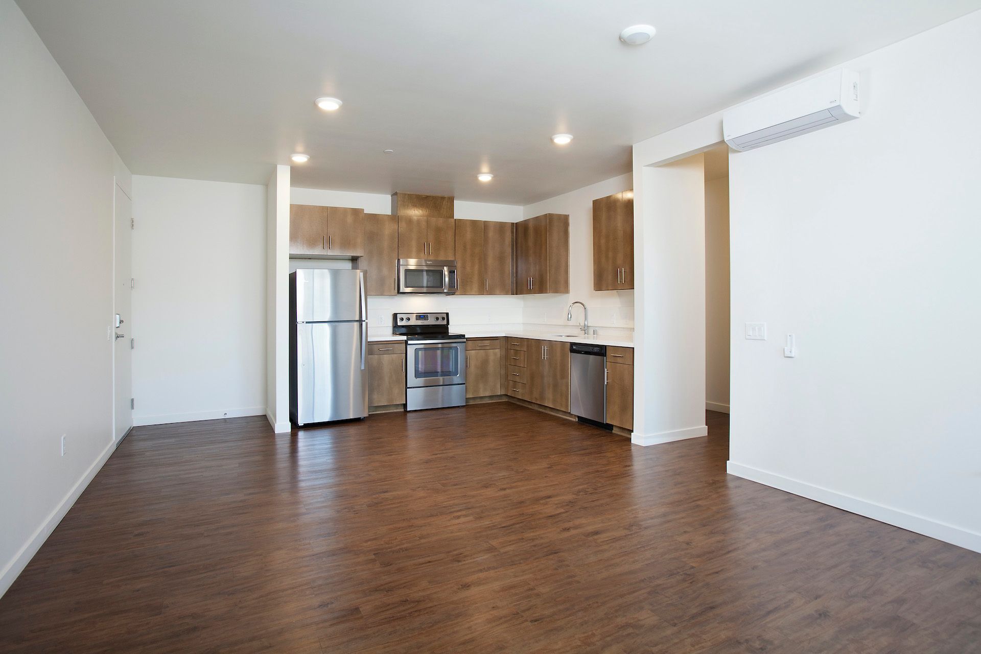 An empty kitchen with stainless steel appliances and wooden cabinets