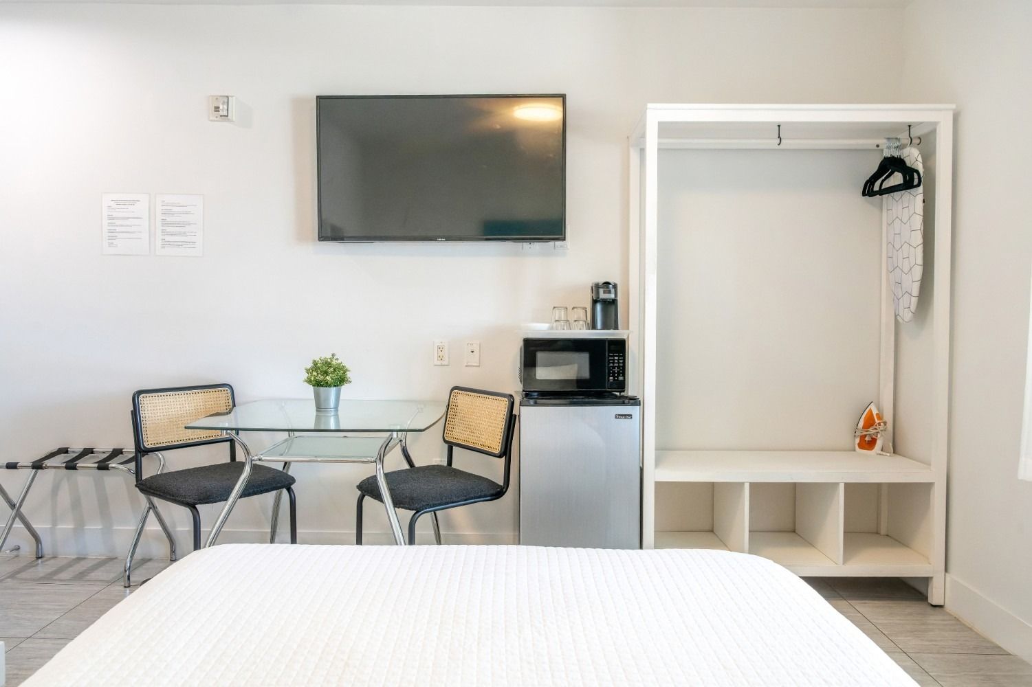Small studio apartment with bed, table, chairs, TV, mini-fridge, microwave, and wardrobe.