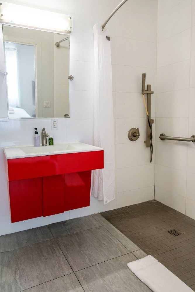 Accessible bathroom with red vanity, walk-in shower, and grab bar.