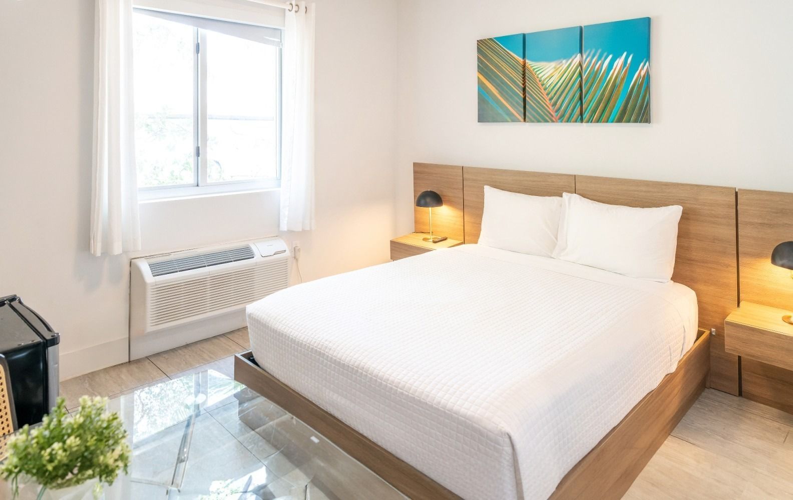 Bedroom with a bed, nightstands, window, AC unit, and artwork.