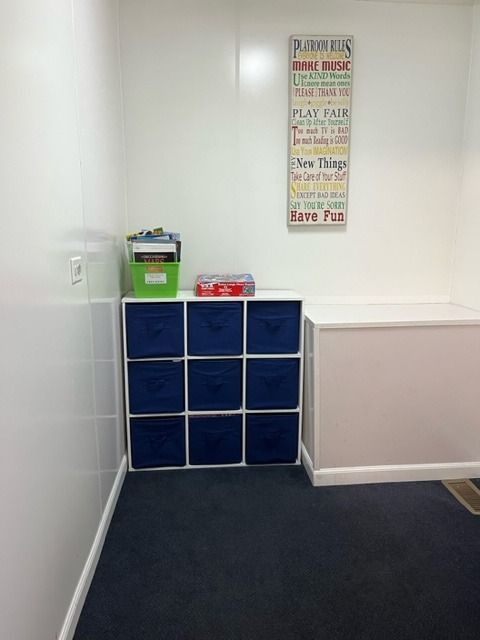 Corner room with white walls, dark blue carpet, and a blue storage cube.