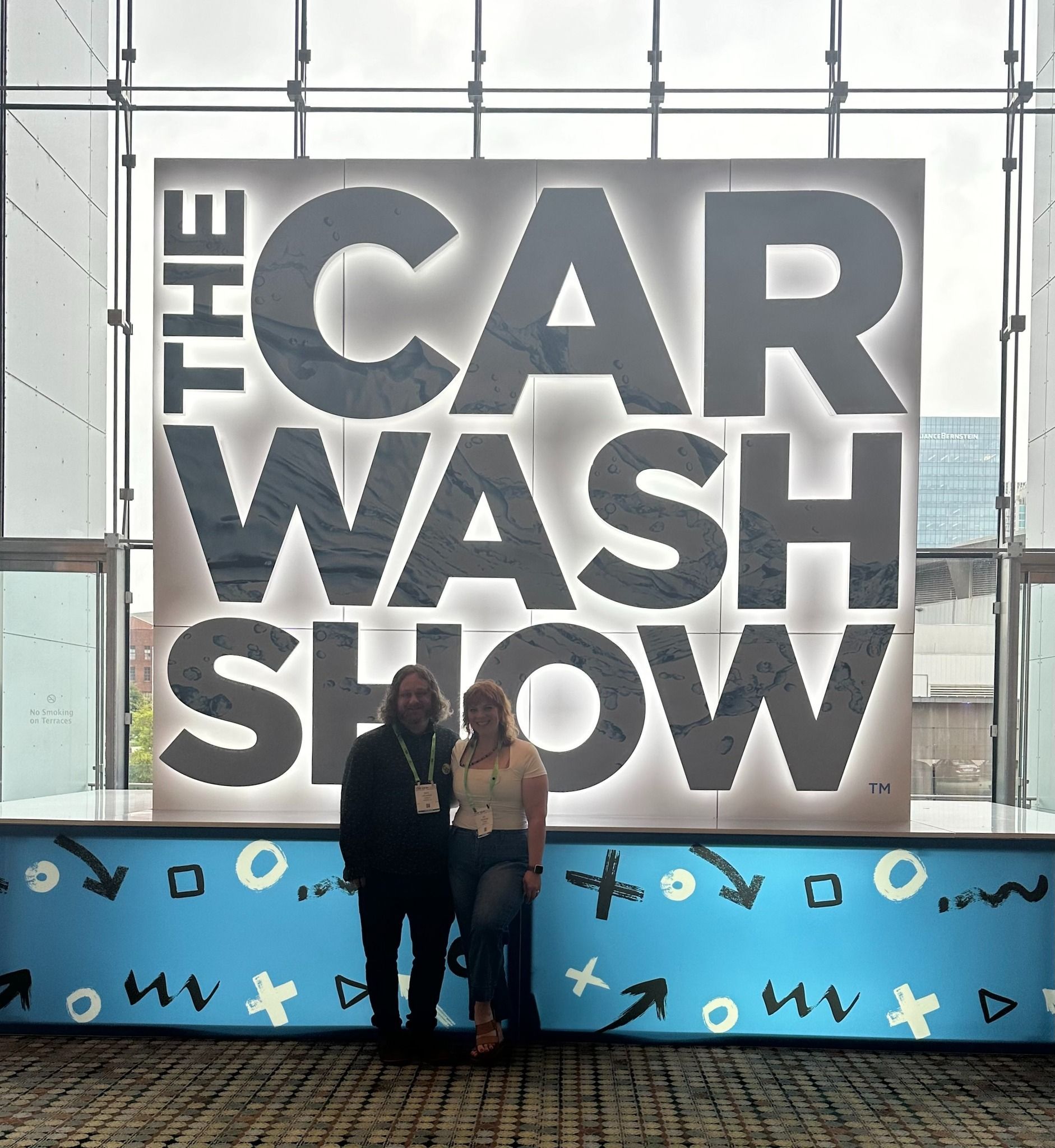 Mike & Mel standing in front of a sign that says the car wash show