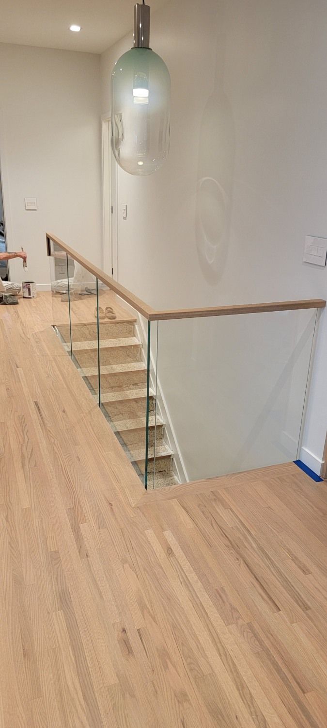 A wooden staircase with a glass railing and a wooden floor