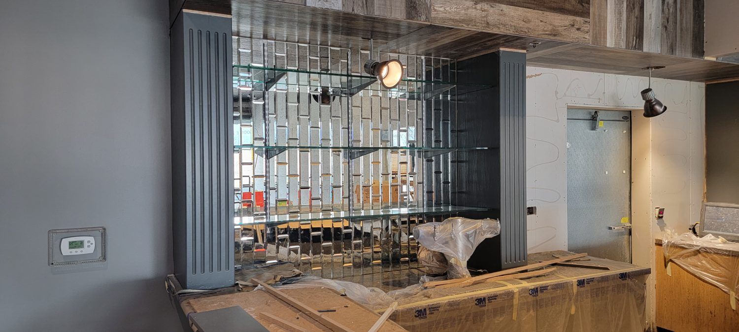 A bar is being built in a room with a mirrored wall