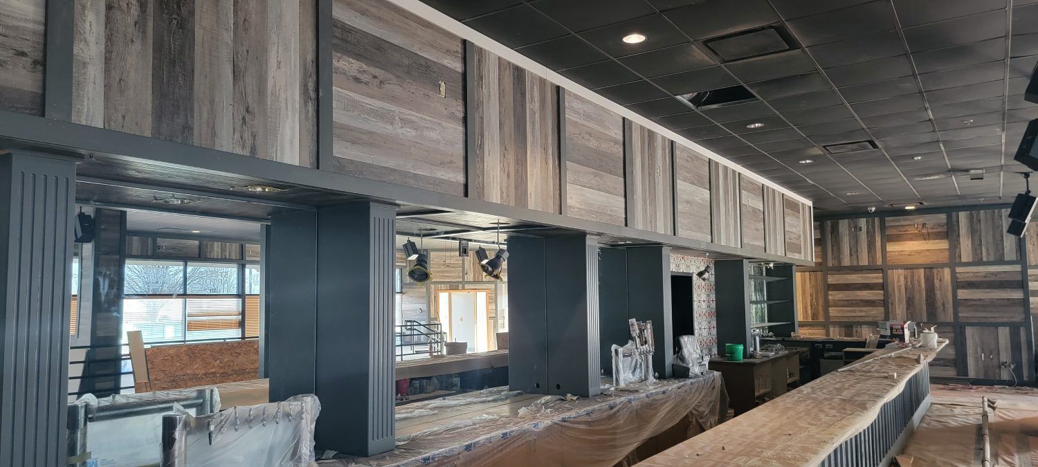A bar is being built in a restaurant with wooden walls and a black ceiling.