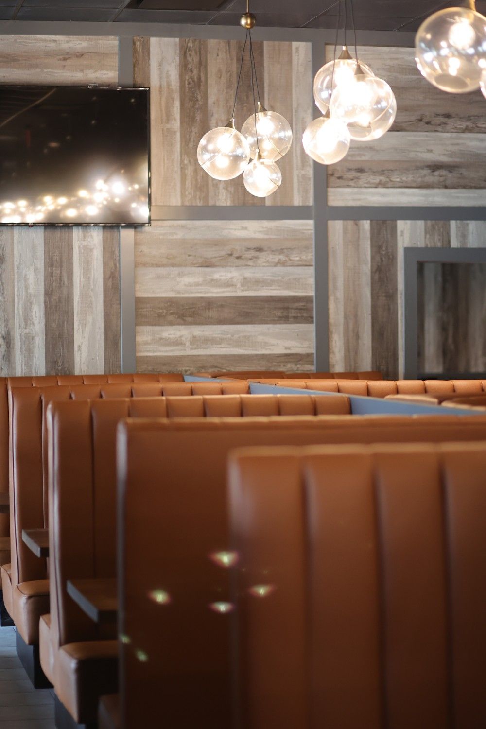 A row of brown leather booths in a restaurant with wooden walls
