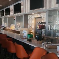 A restaurant with a long bar and orange chairs