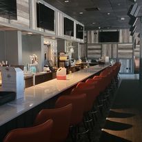 A long bar with red chairs in a restaurant