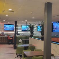 A restaurant with tables and chairs and televisions on the wall