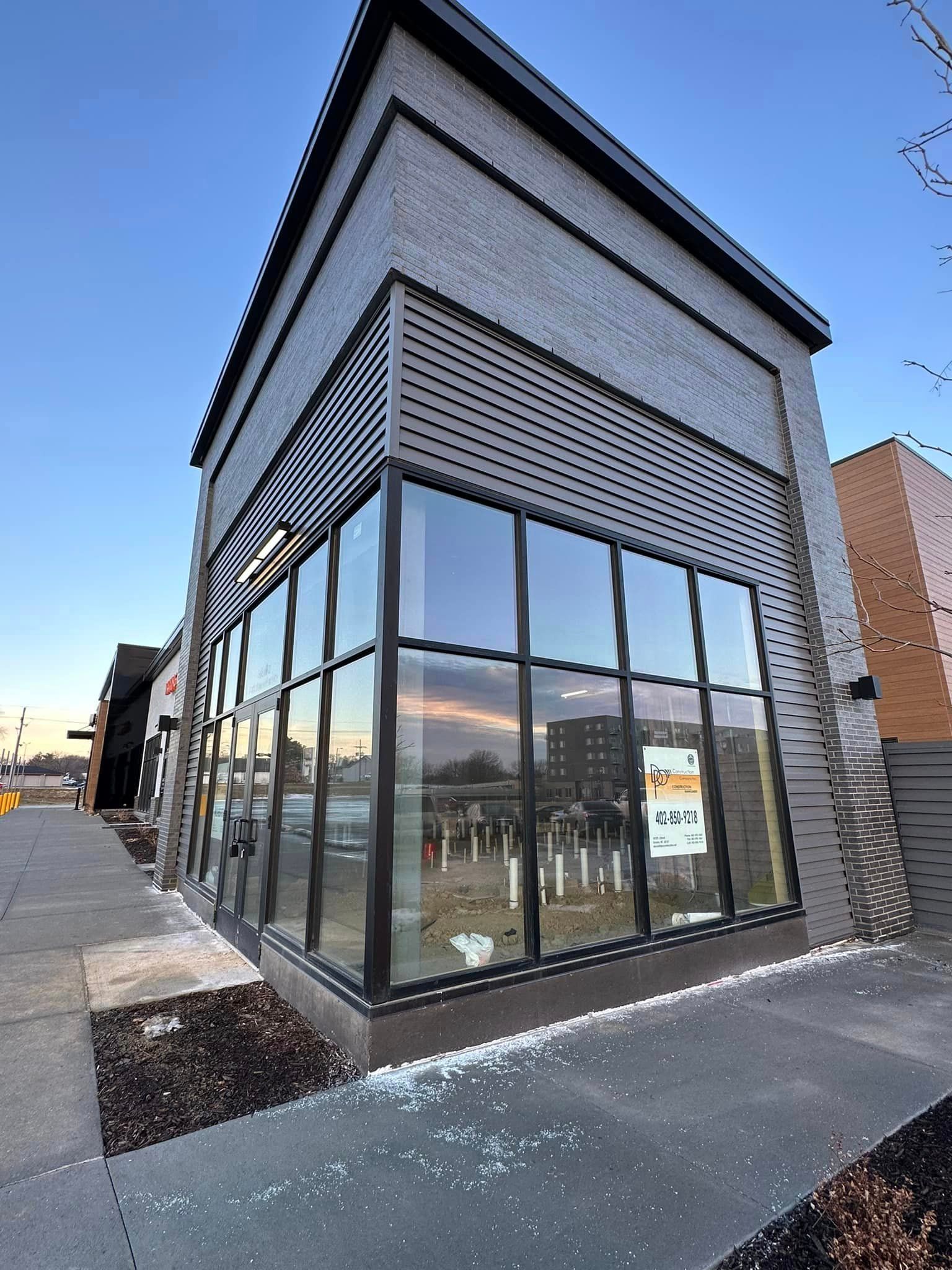 A building with a lot of windows and a sign on the sidewalk