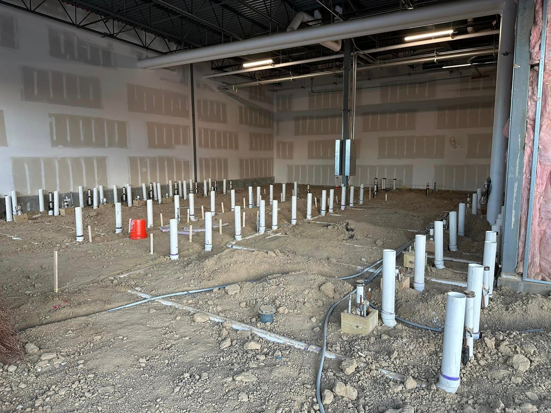 A building under construction with a lot of pipes on the ground