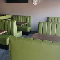 A restaurant with cozy green chairs