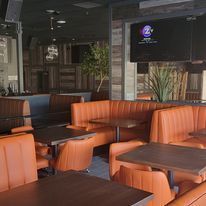 A restaurant with orange chairs and tables and a flat screen tv