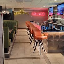 A restaurant with a long bar and a sign that says no spaghetti palace