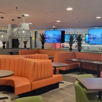 A restaurant with orange benches and green chairs and tables