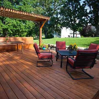 A wooden deck with a table and chairs under a pergola.