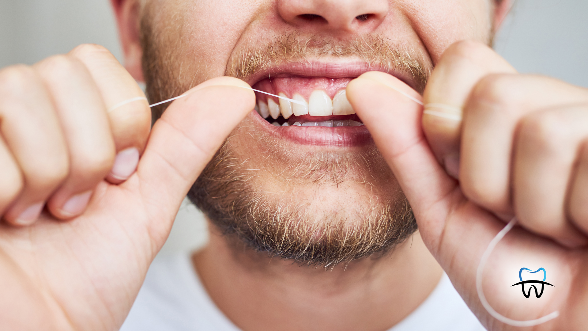 Person flossing teeth, mouth open, holding floss taut.