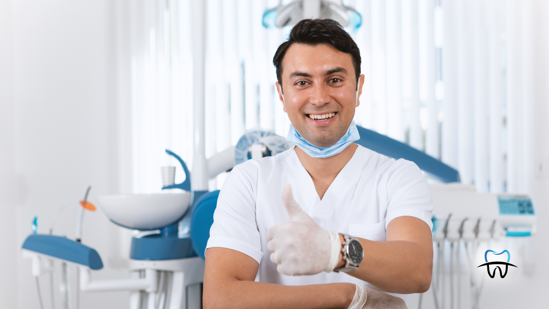 Dentist in white coat gives thumbs up, smiling in dental office with blue equipment.