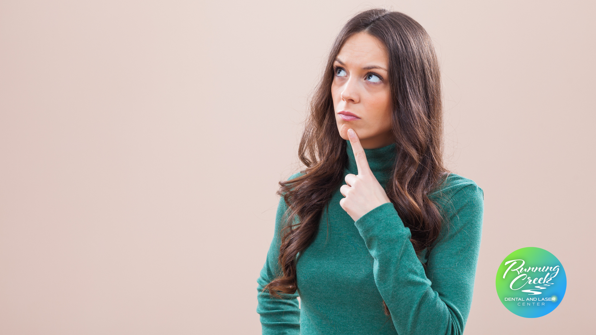A woman in a green sweater is thinking with her finger on her chin.