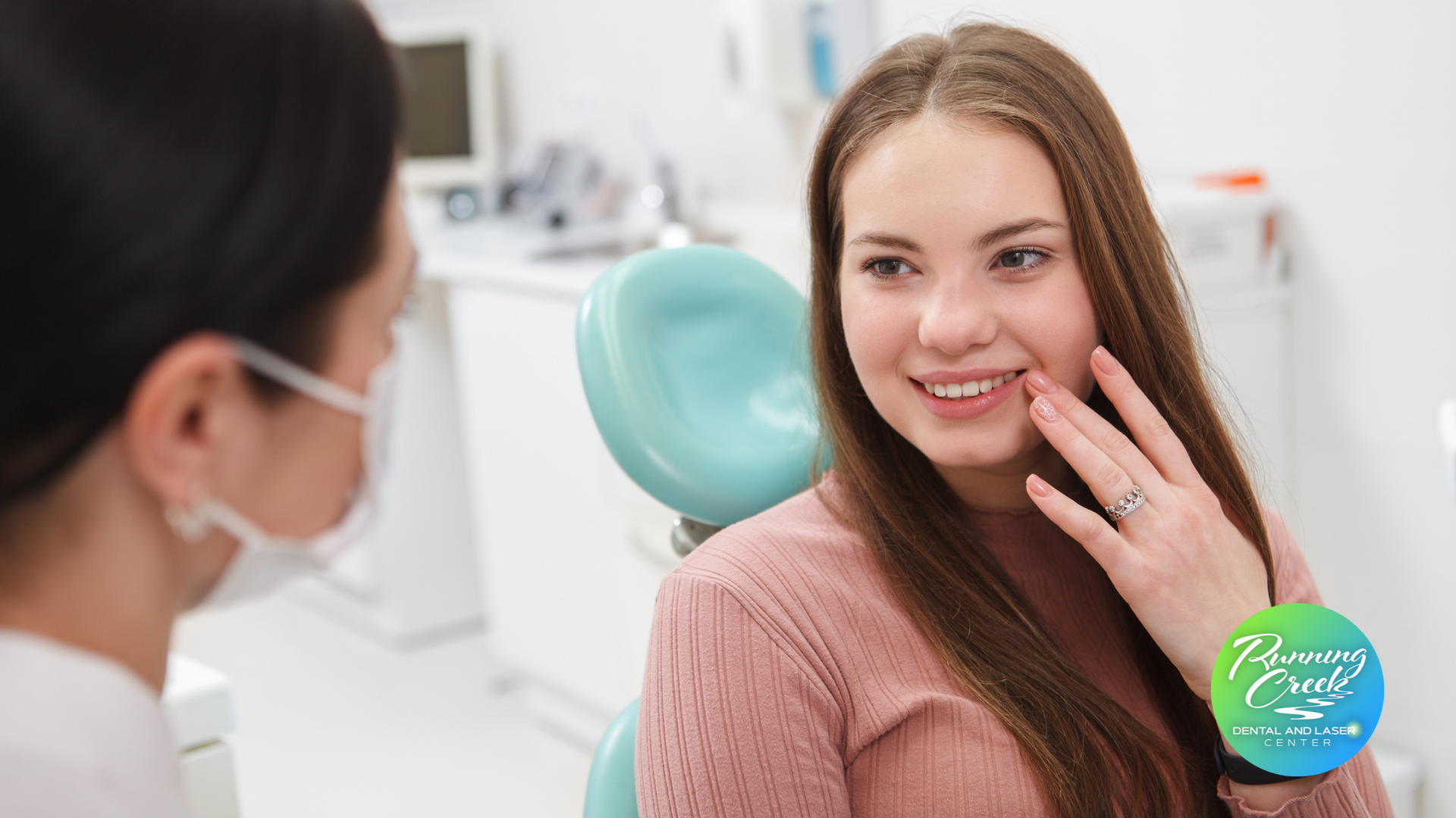 A woman is sitting in a dental chair talking to a dentist.