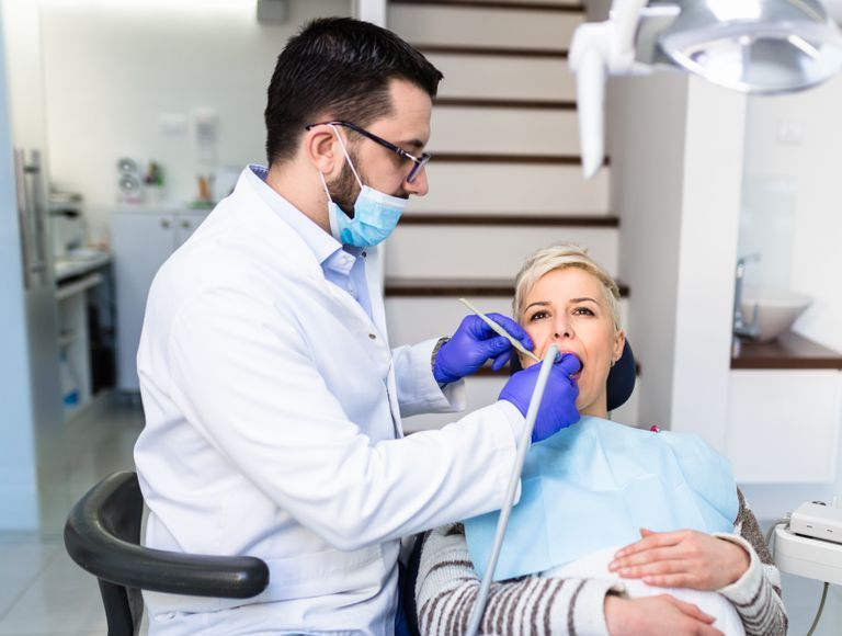Dentist examining a patient's teeth in a dental office.