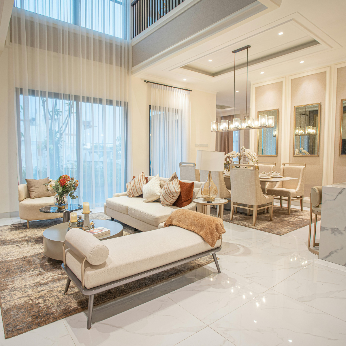Luxurious living room with light-colored furniture, large windows, and a dining area.