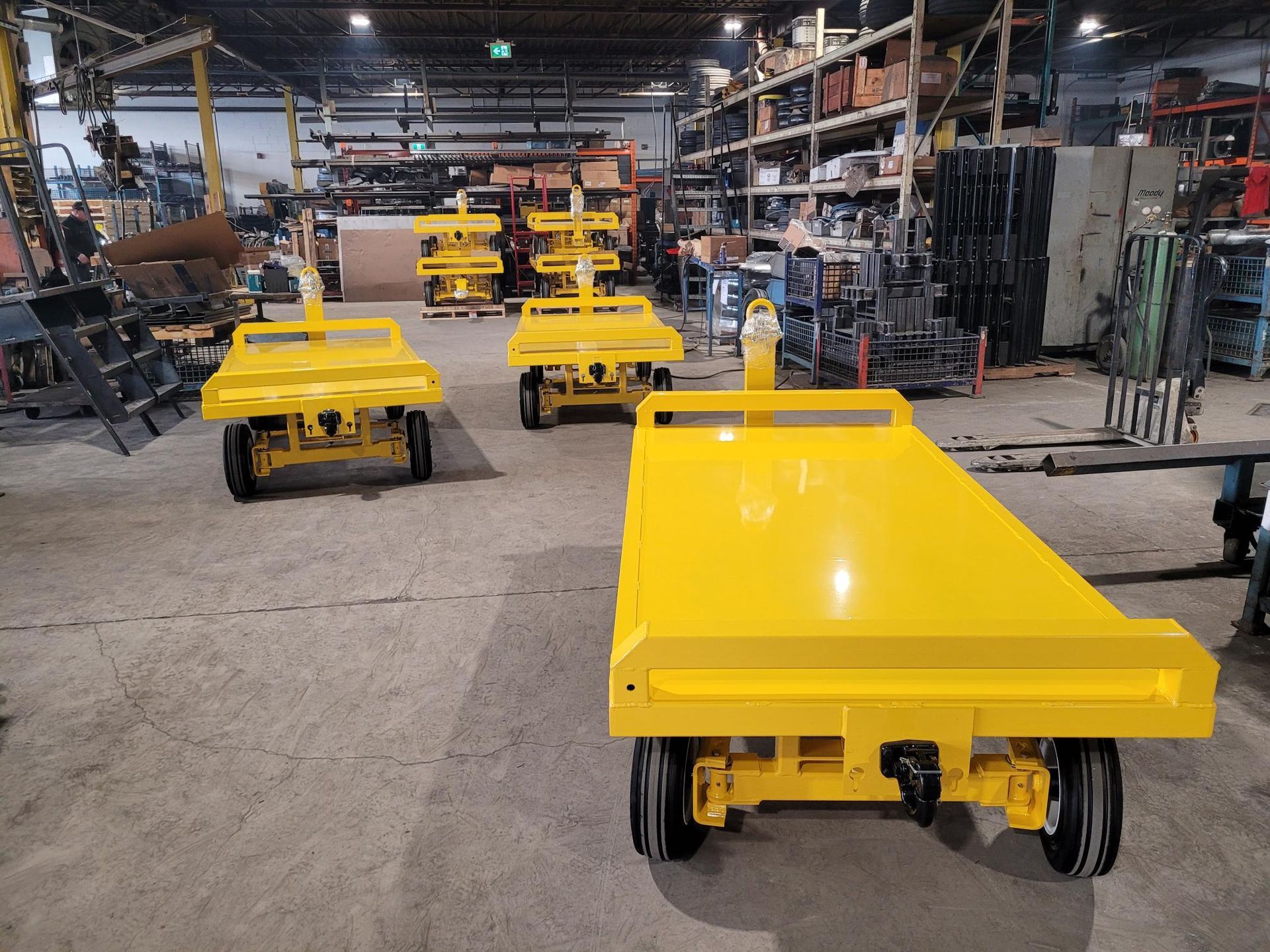 A row of yellow carts are sitting in a warehouse.
