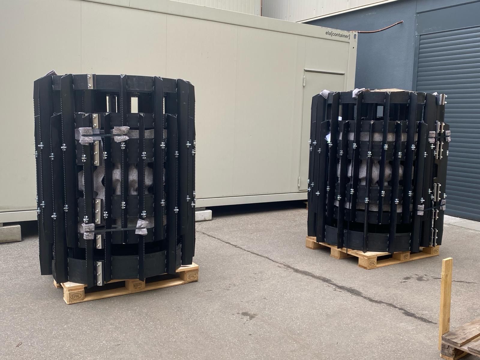 Two rolls of rubber tracks are stacked on top of each other on a wooden pallet.