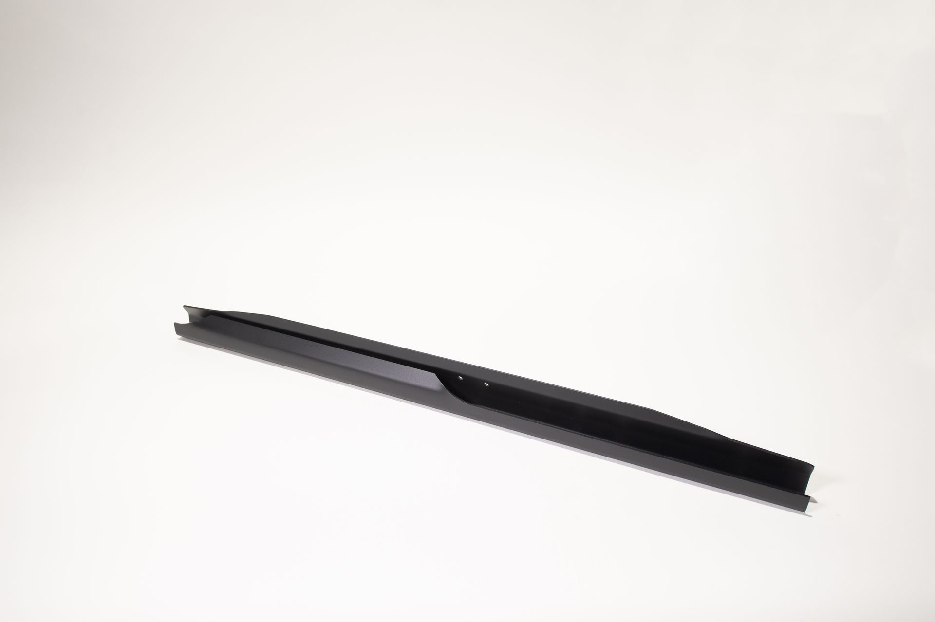 A black pen is sitting on a white surface.