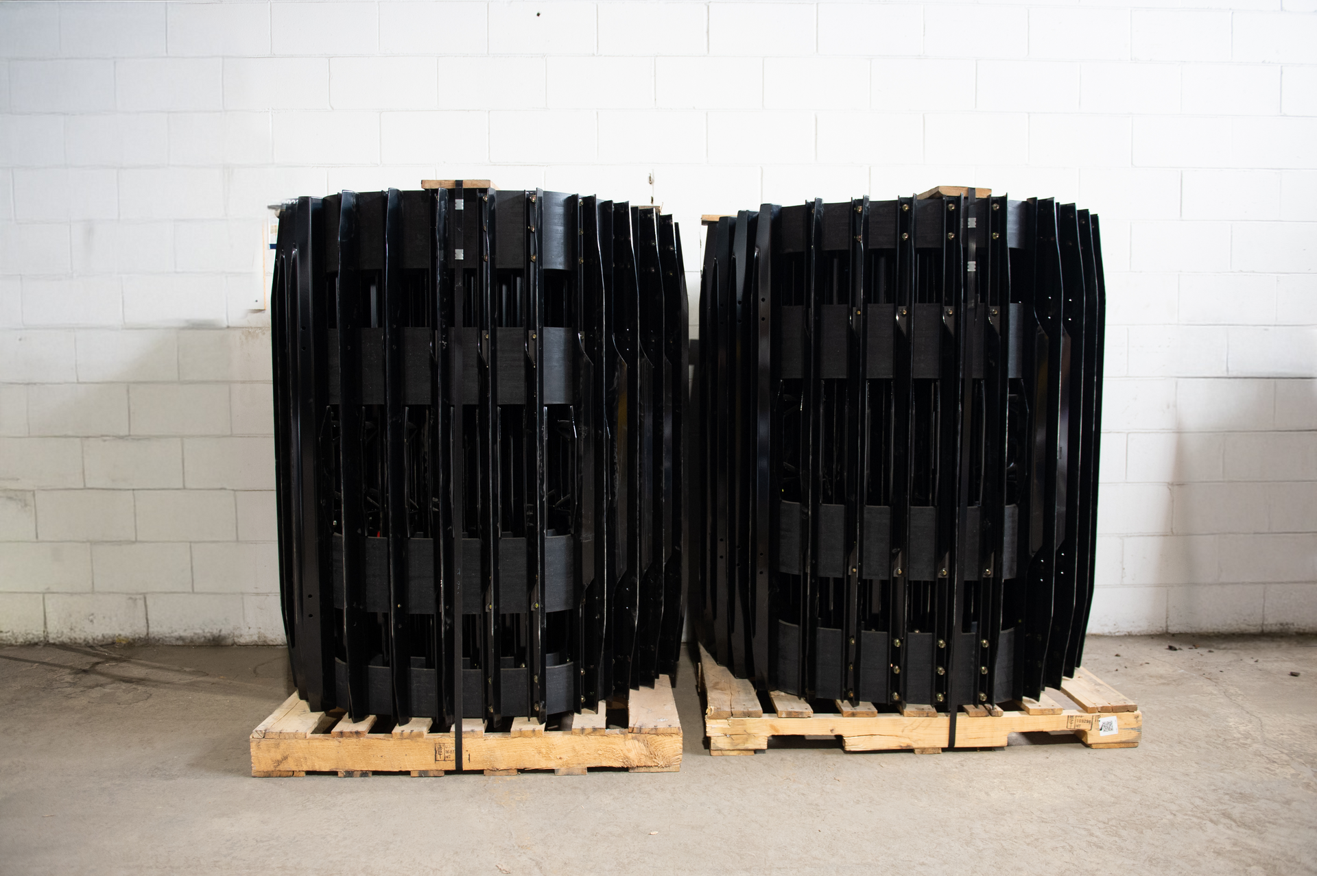 Two rolls of rubber tracks are stacked on top of each other on a wooden pallet.