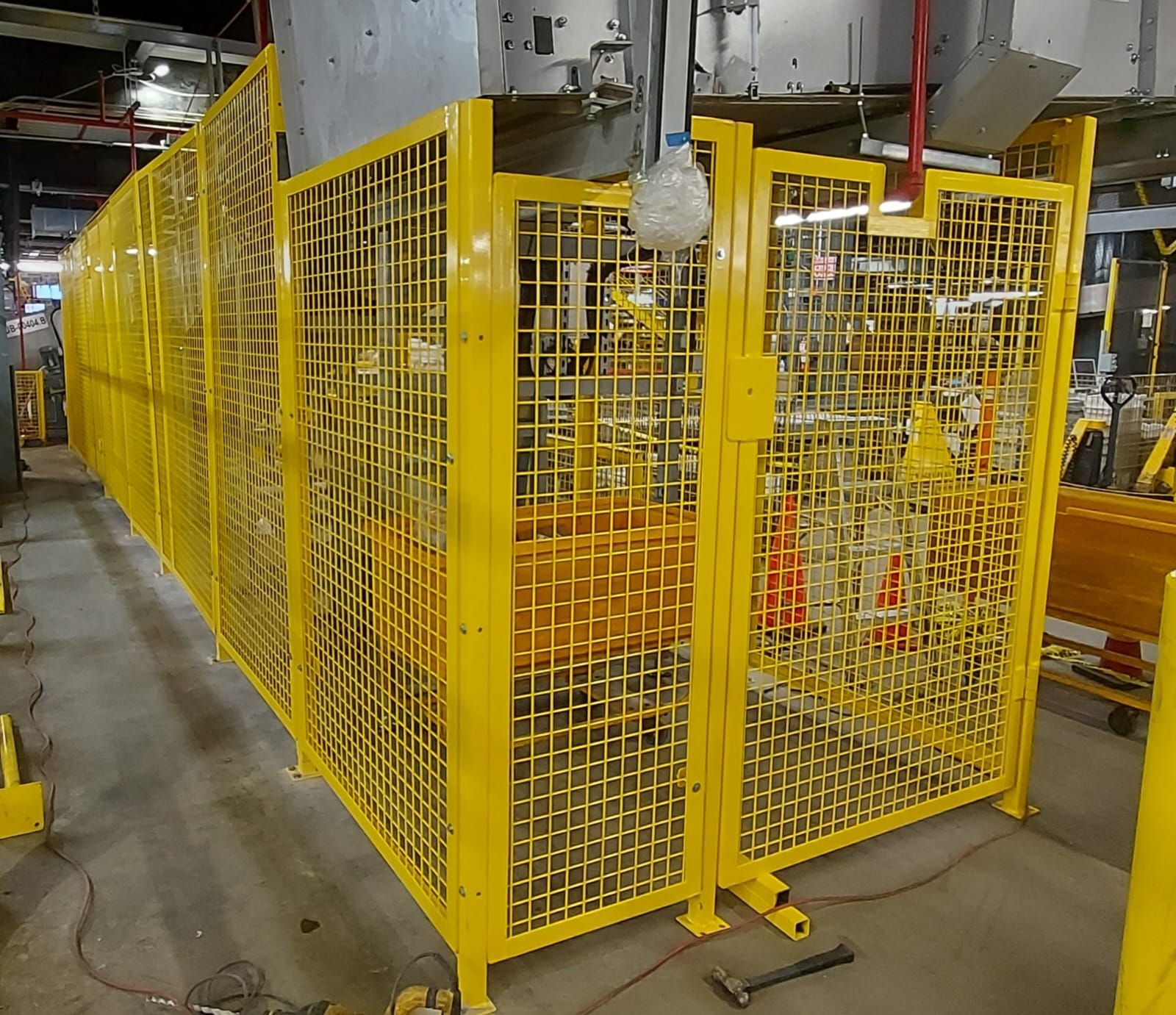 A yellow cage with a hammer on the floor