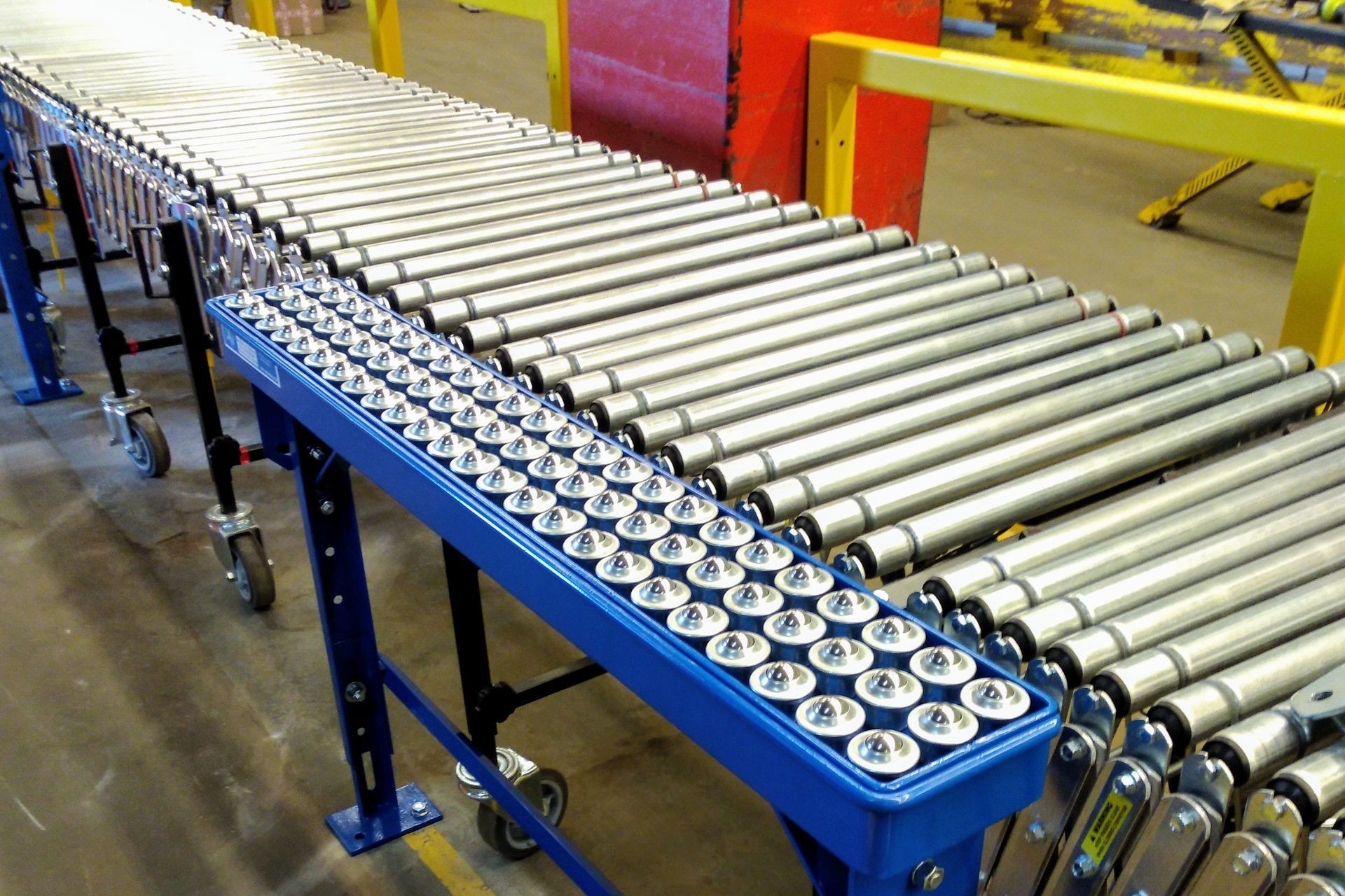 A conveyor belt filled with metal rollers in a factory.